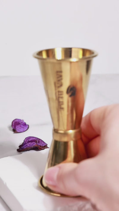 Eingießen von Lavabelle in Jigger, dann Eiswürfel in Aperitif-Glas und mit Lavabelle aus dem Jigger und danach Tonic Water aufgießen